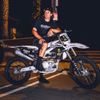 Man sitting on a dirt bike at night with palm trees in the background