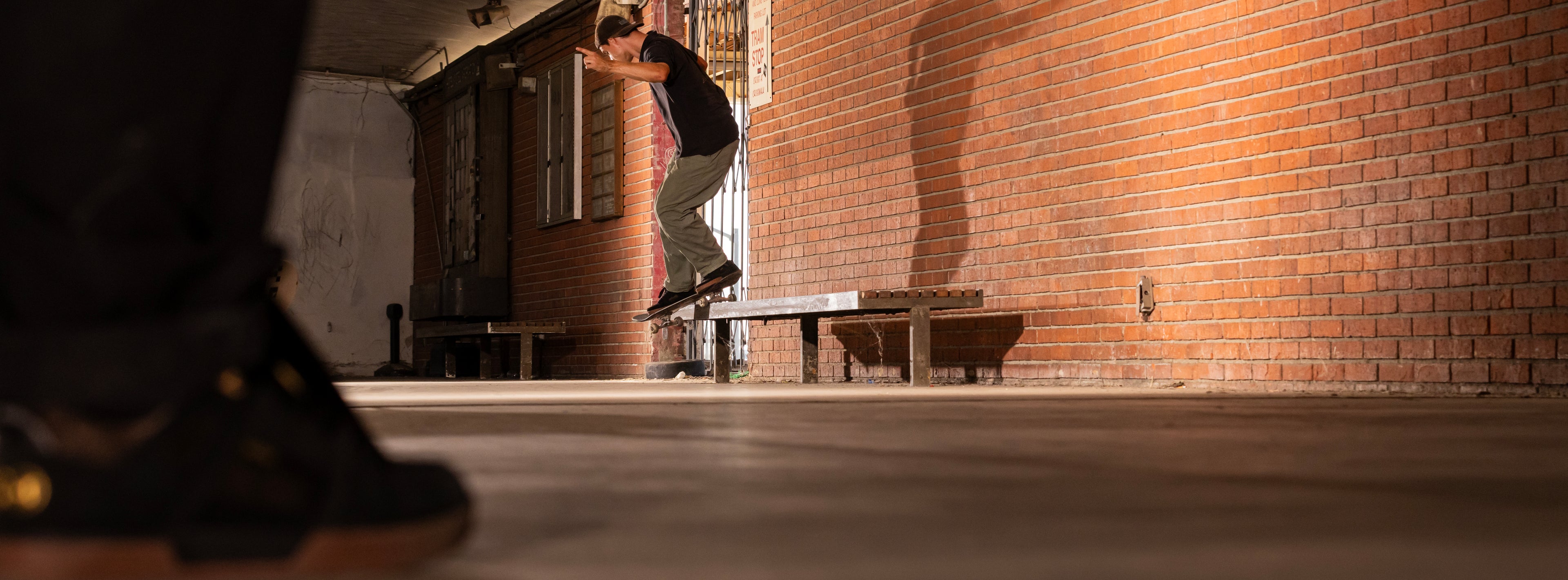 Person skateboarding in an urban setting with a brick wall and concrete floor.