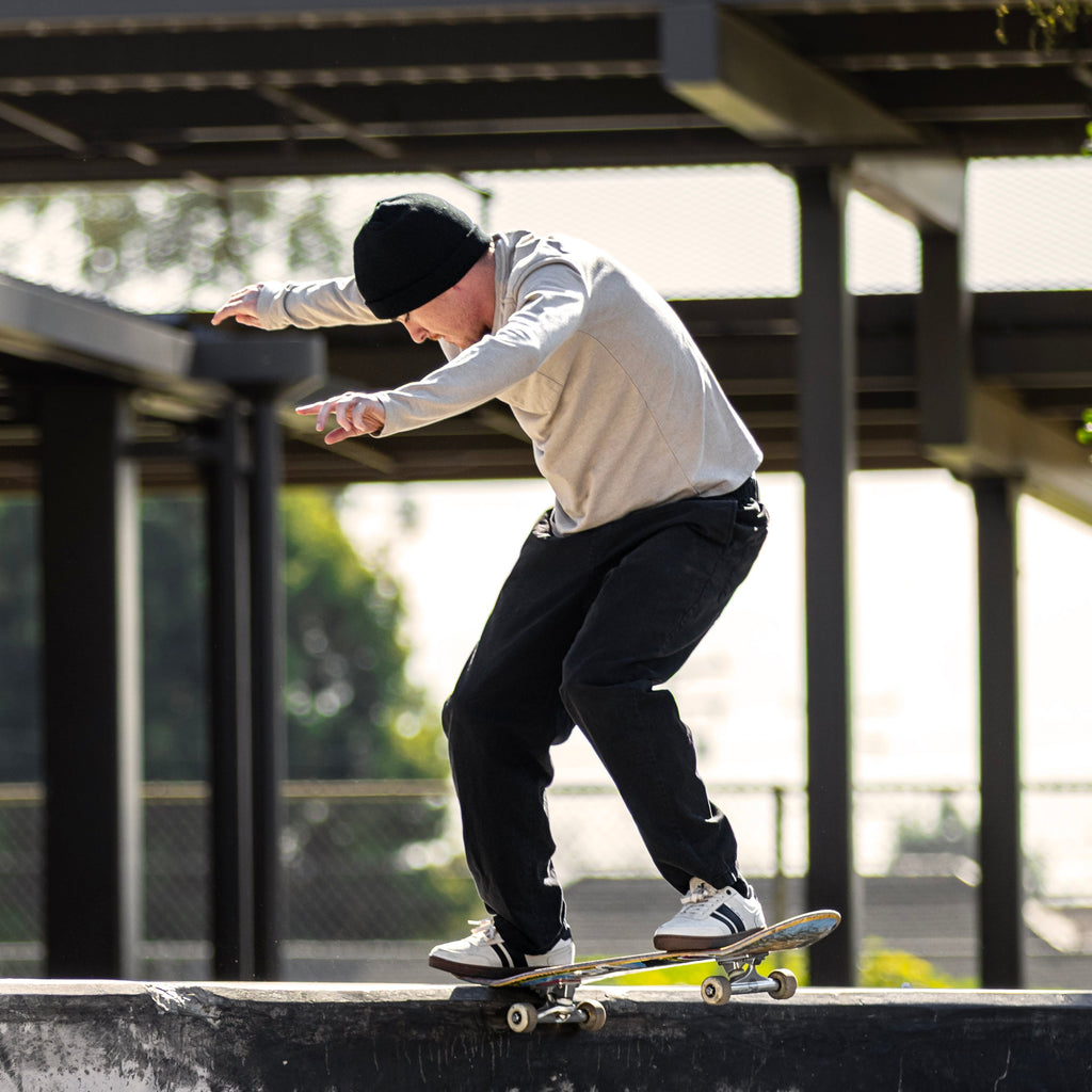 Person skateboarding on a concrete ledge with a building and trees in the background