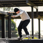 Person skateboarding on a concrete ledge with a building and trees in the background