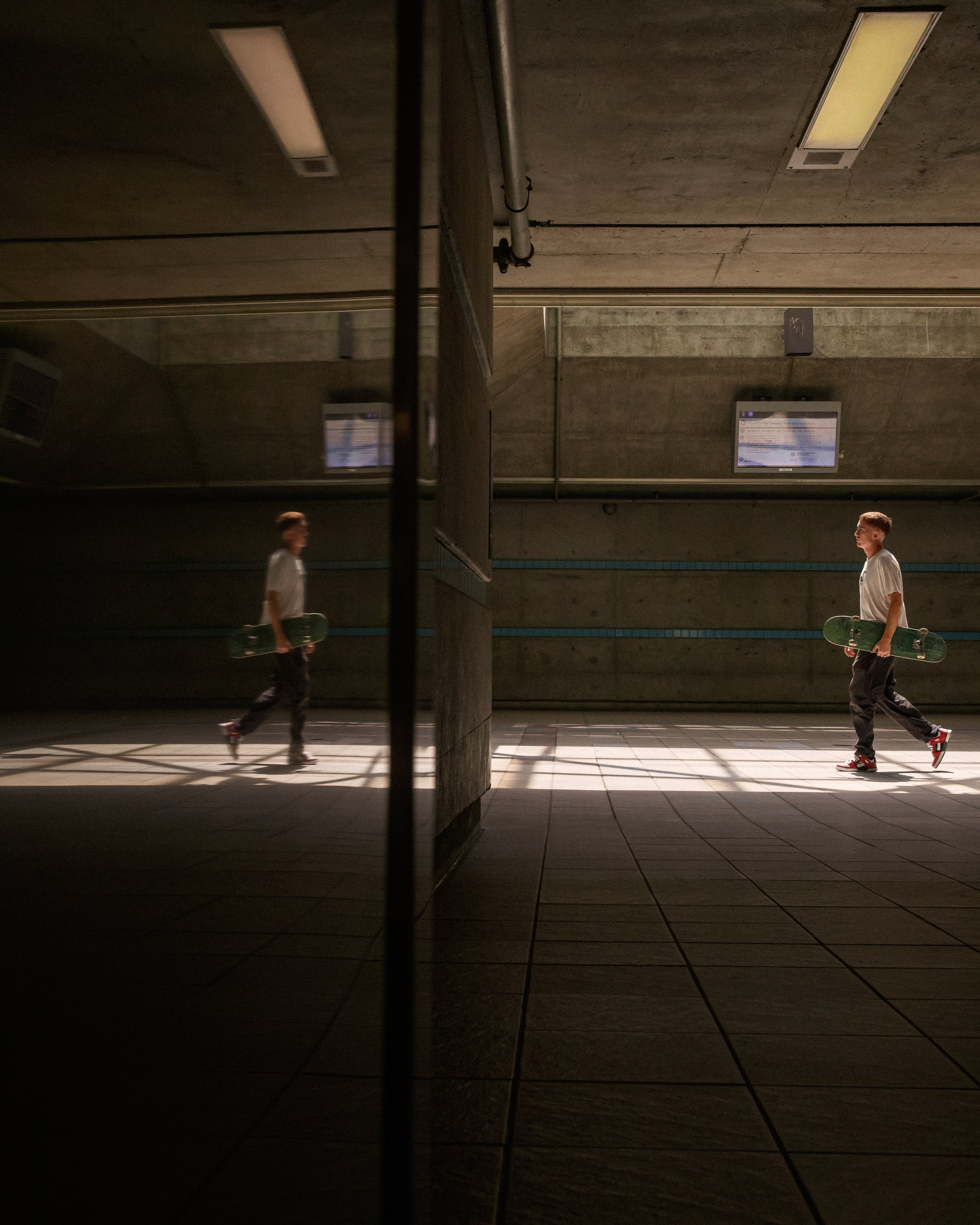 Person walking with a skateboard in a dimly lit hallway