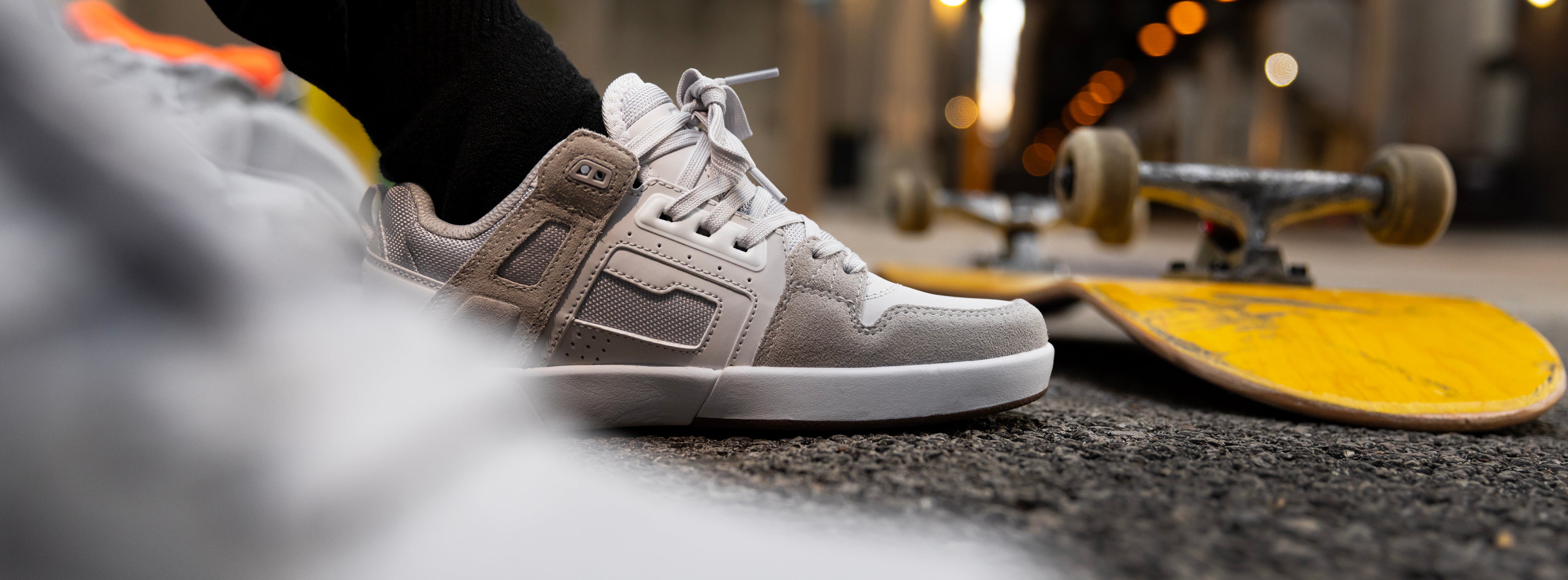 Close-up of a person wearing brown sneakers with white soles on a street.