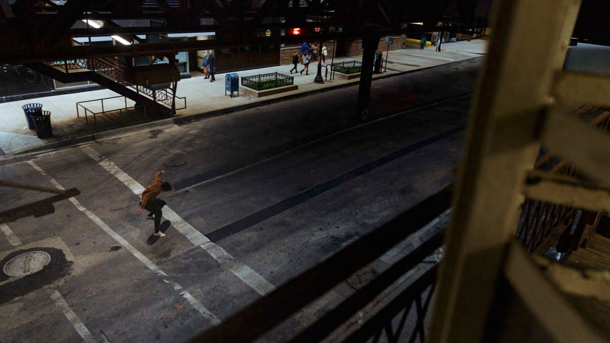Skateboarder on an urban street at night with a bridge in the foreground